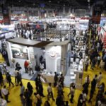 Busy exhibition hall in India showcasing Make in India initiatives with businesses, trade booths, and visitors exploring innovation in 2025